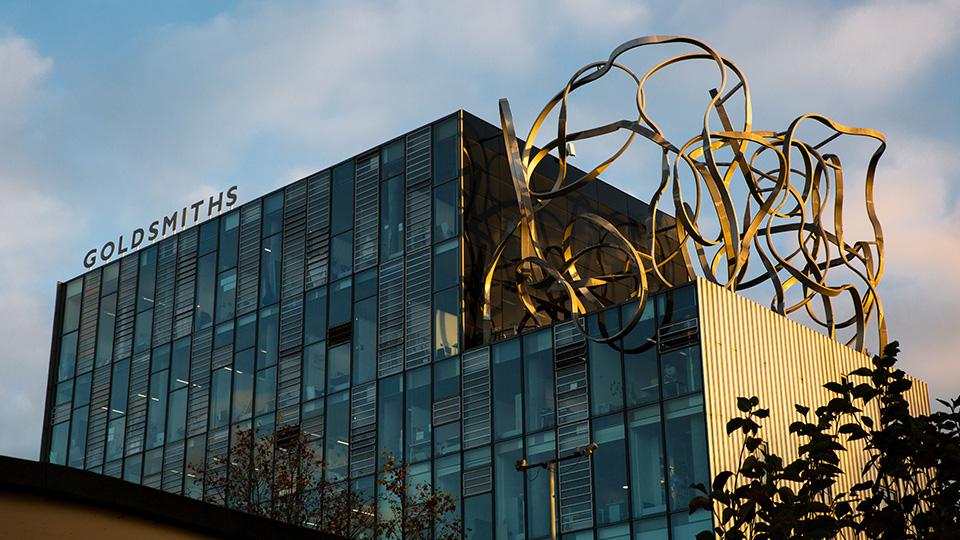 A modern glass building is lit by evening sunlight