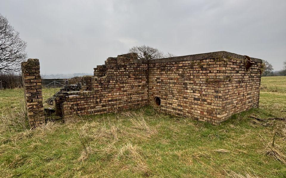 A brick bunker with a blast wall in a field